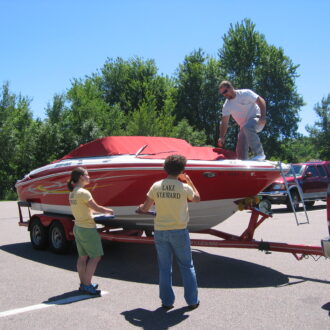 Two boat launch stewards speak with a man preparing to launch his boat.